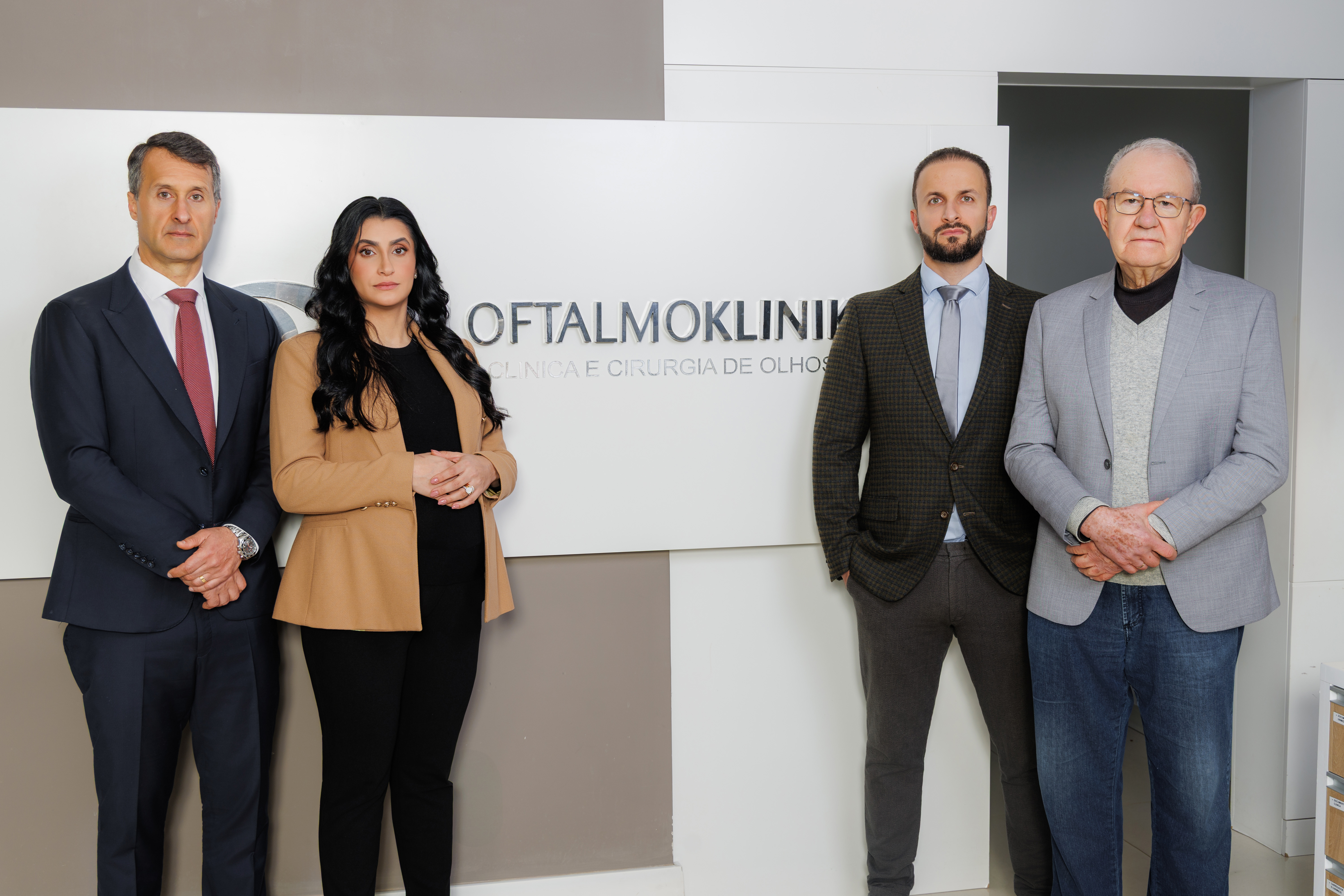 Equipe médica dentro da clínica, em frente ao nome e ao logo da Oftalmoklinik